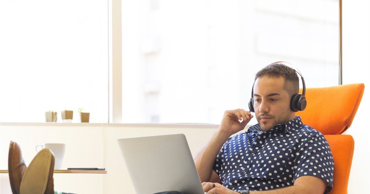 Man listening through headphones while reviewing a program on his laptop