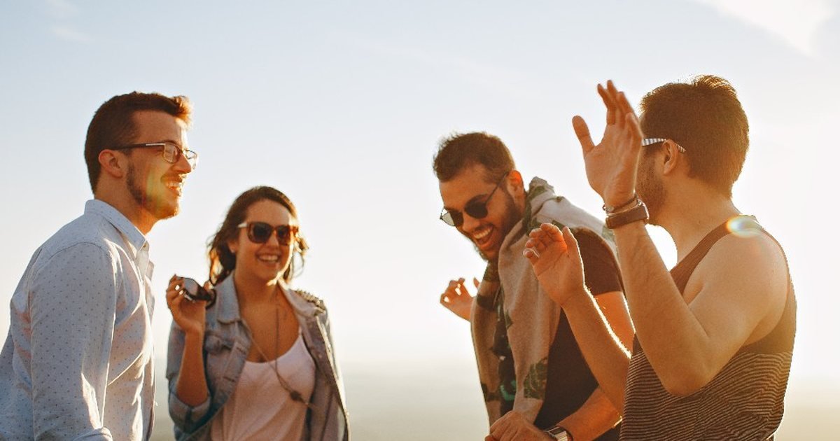 Group of friends laughing together outdoors at sunset
