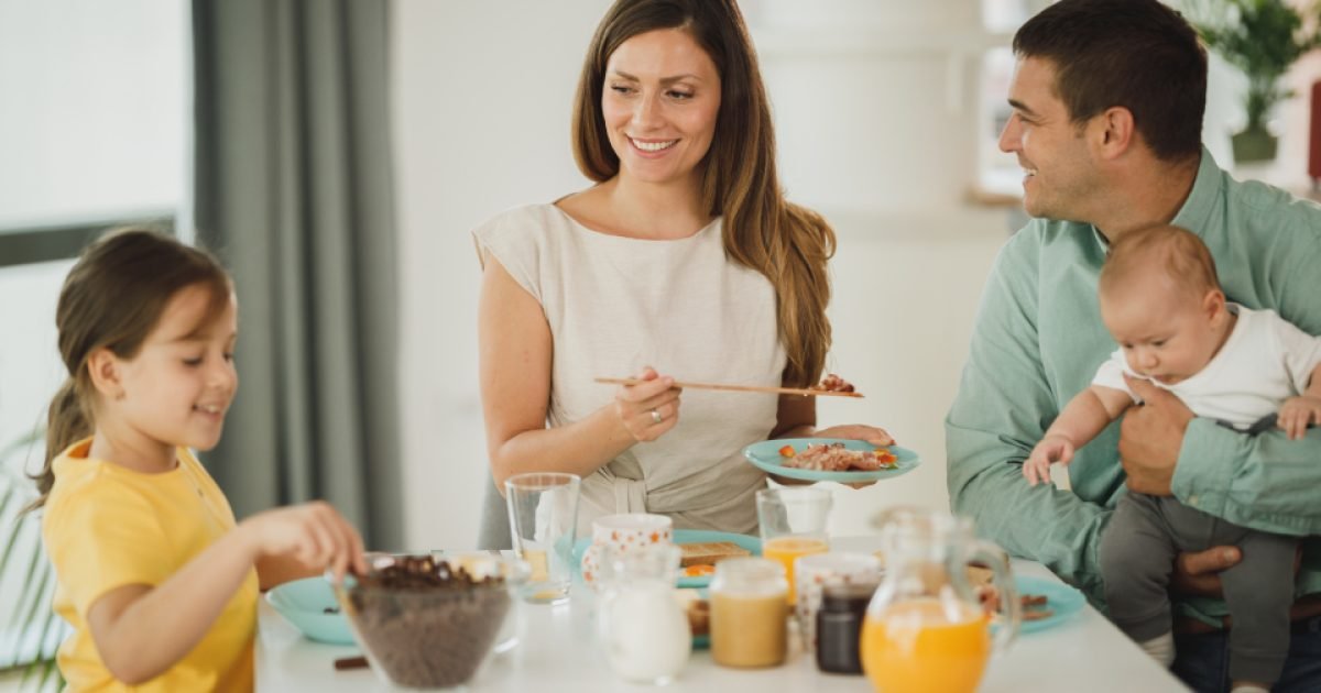 Family with two children eating breakfast together at a kitchen table