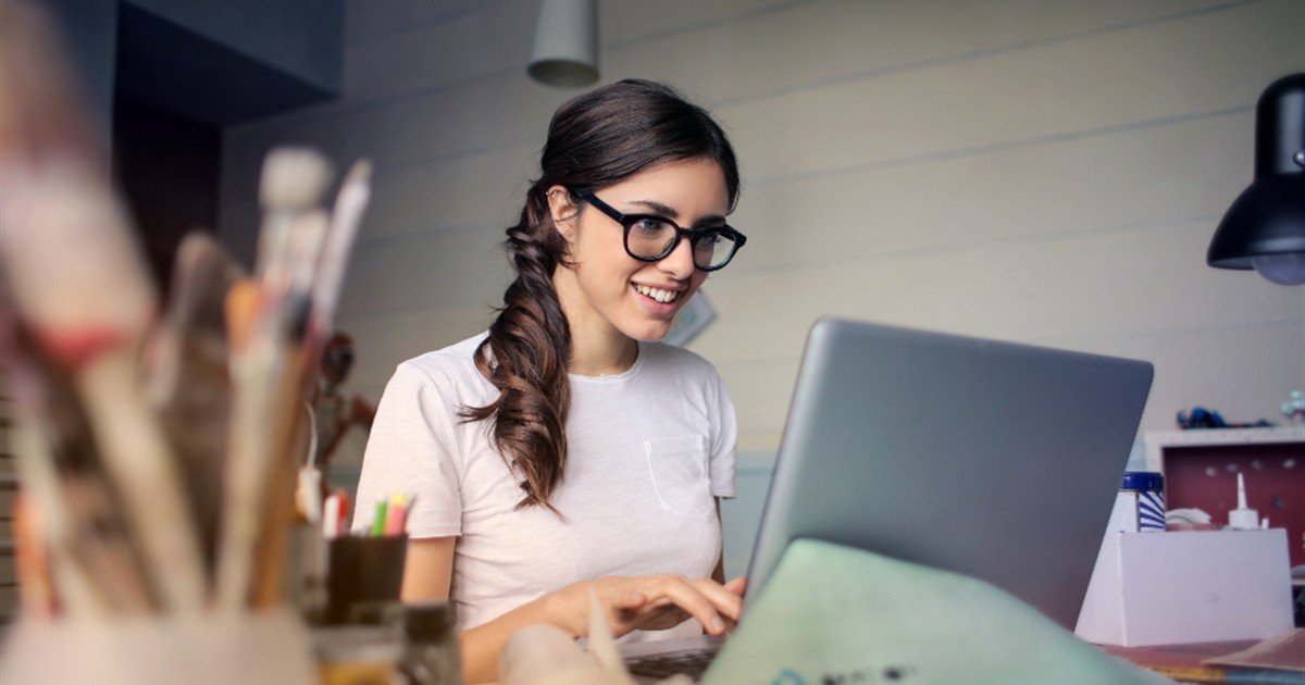 Woman wearing glasses working on a laptop at her desk