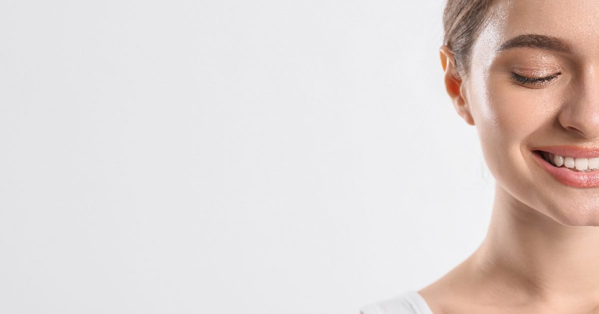 Close-up of a smiling woman's face against a plain background