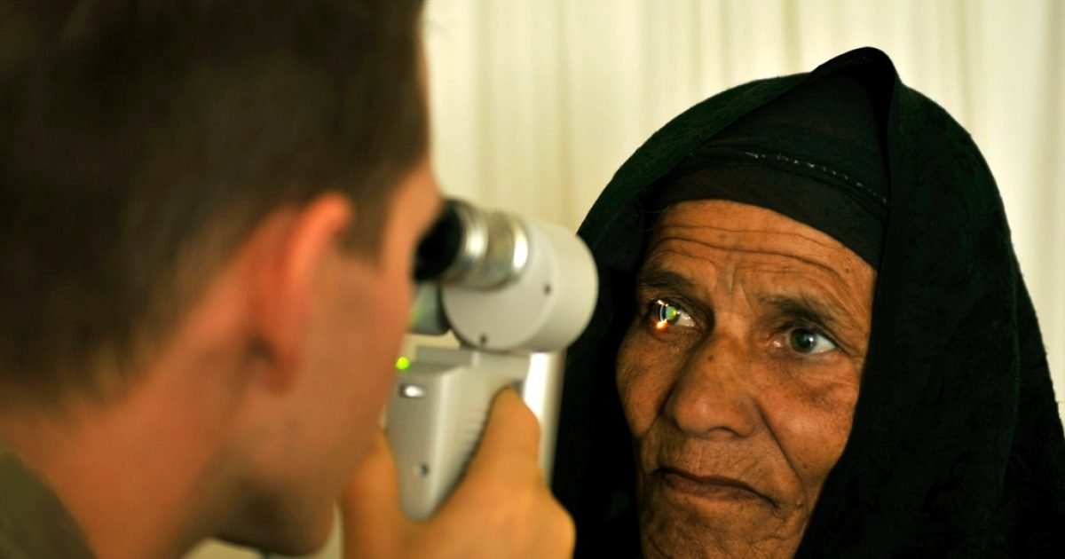 Clinician examining an older woman's eye with a handheld instrument