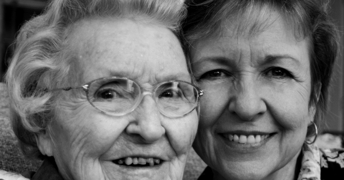 Portrait of a senior mother and her adult daughter smiling side by side