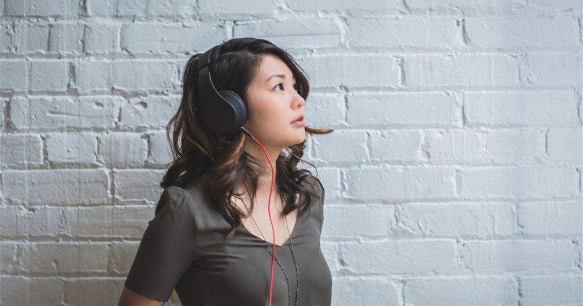 Woman listening on over-ear headphones while comparing audio programs