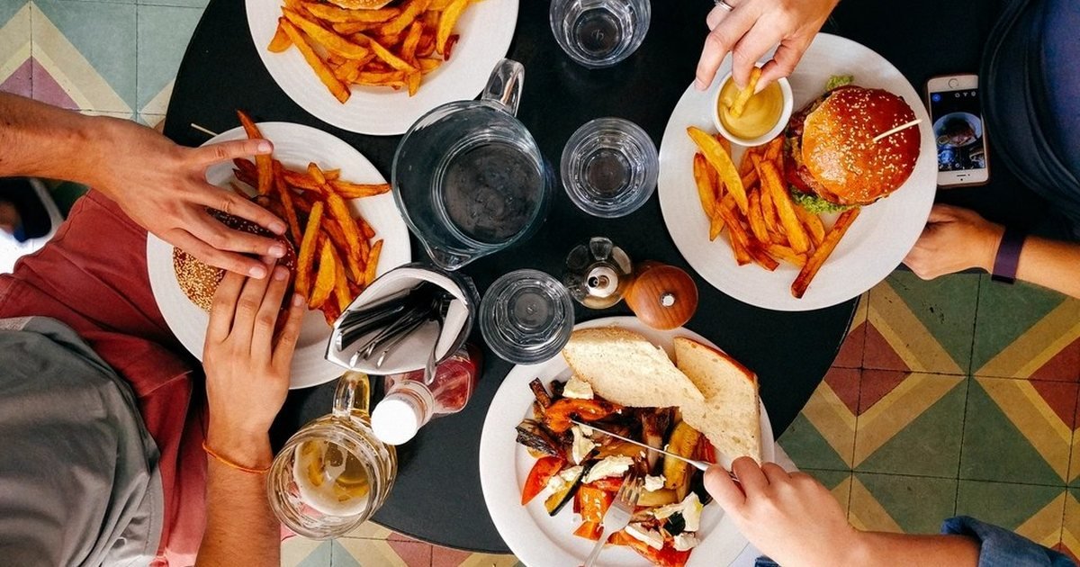 Overhead view of four people sharing a meal around a cafe table