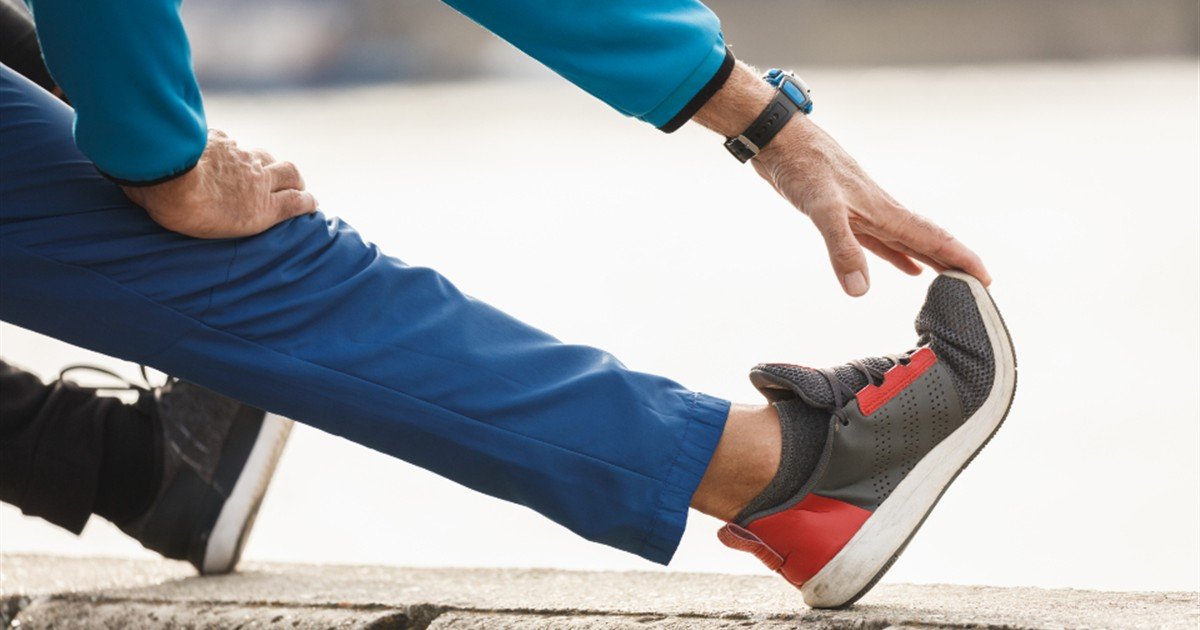 Senior man holding his knee while stretching his leg before exercise
