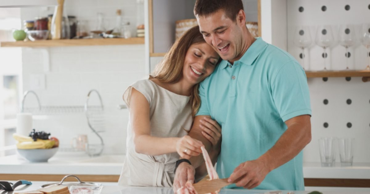 Couple preparing food together at a kitchen counter with vegetables and eggs