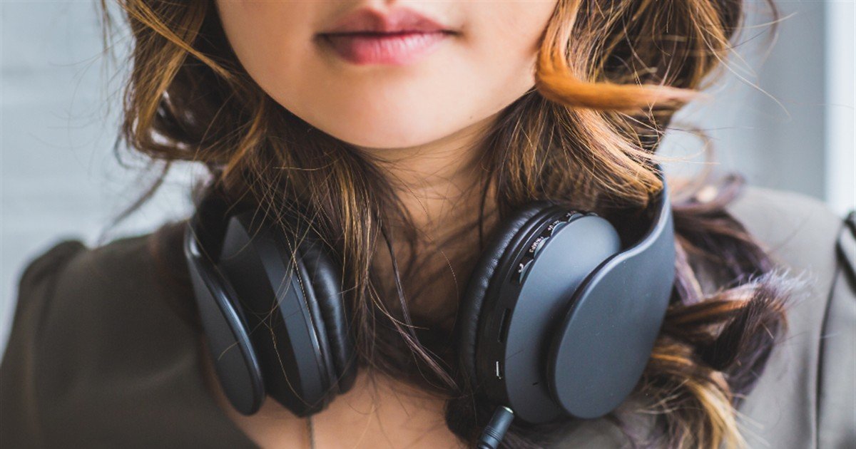 Woman with headphones around her neck getting ready for a relaxation session