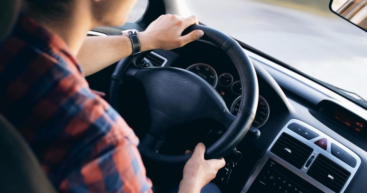 Man behind the steering wheel of a car with both hands on the wheel