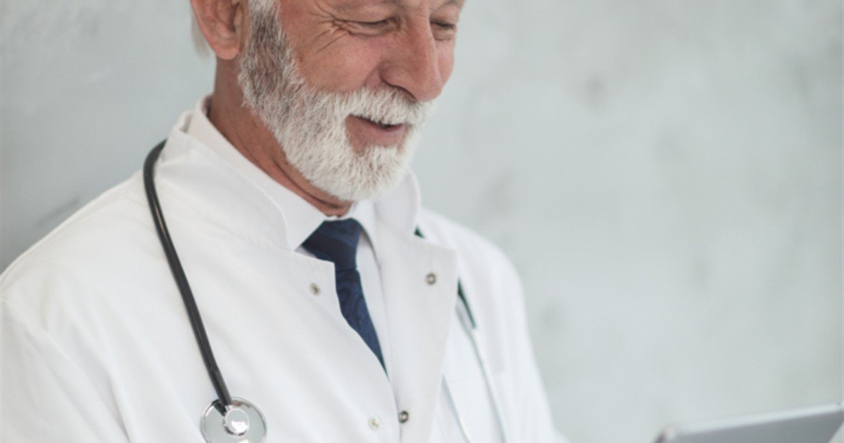 Senior male doctor reviewing patient information on a tablet