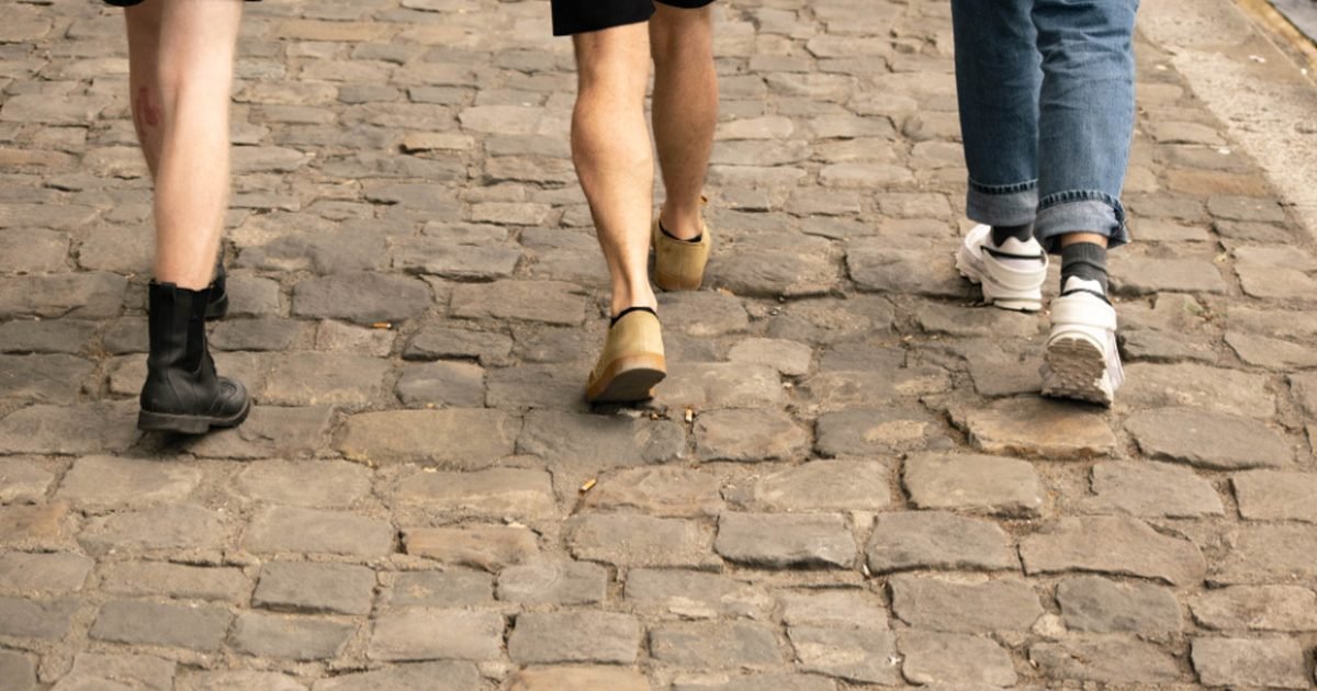 Three people walking along a cobblestone city street