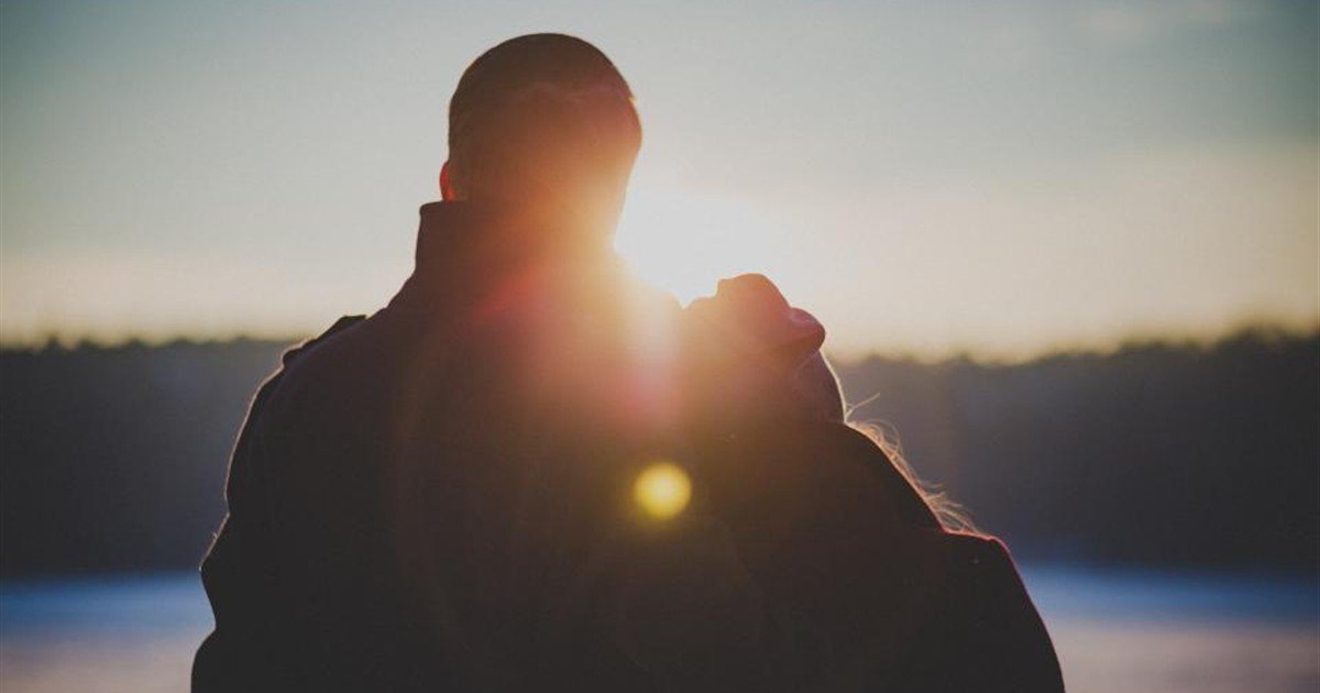 Couple standing close together at sunset as the light fades between them